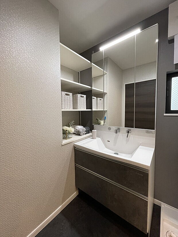 【【当社施工例】洗面室】身支度の際に重宝する三面鏡タイプの洗面台です。洗面ボウル下、三面鏡裏に収納スペースがあります。更に洗面台横に、タオルや下着の収納に便利な棚も備わっています。