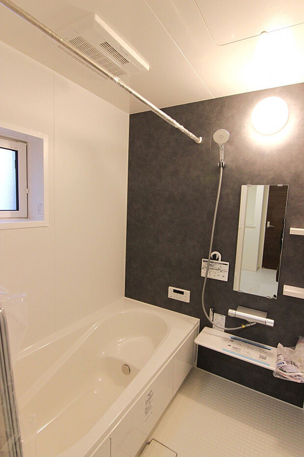 【【1号棟:浴室】】白を基調とし、モルティオダークの壁を一面に敷いたシックな雰囲気の浴室。浴室暖房換気乾燥機付で冬は温かく、雨の日のお洗濯も安心。浴槽は温かさが続くサーモバスS構造。