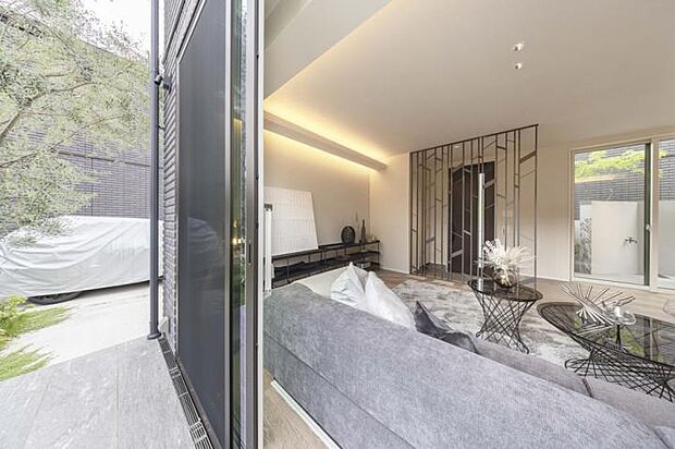 【No.6_LDK2(撮影_2025年9月)】仕切りの格子越しに奥まで広がるリビングテラスと緑が空間の豊かさを感じさせます。樹木に見えるオブジェとなり、テーマの「森に棲む」を体現します。