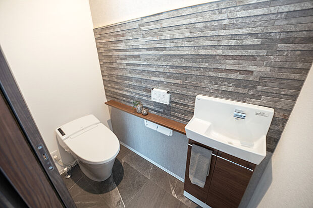 【【1階トイレ/C号地モデルハウス】】タンクが視界に入らず、スッキリとした印象に。無理のない姿勢で手洗いができ、水が跳ねにくい手洗キャビネットを備えています。カウンターにはグリーンを飾ると空間の差し色に。