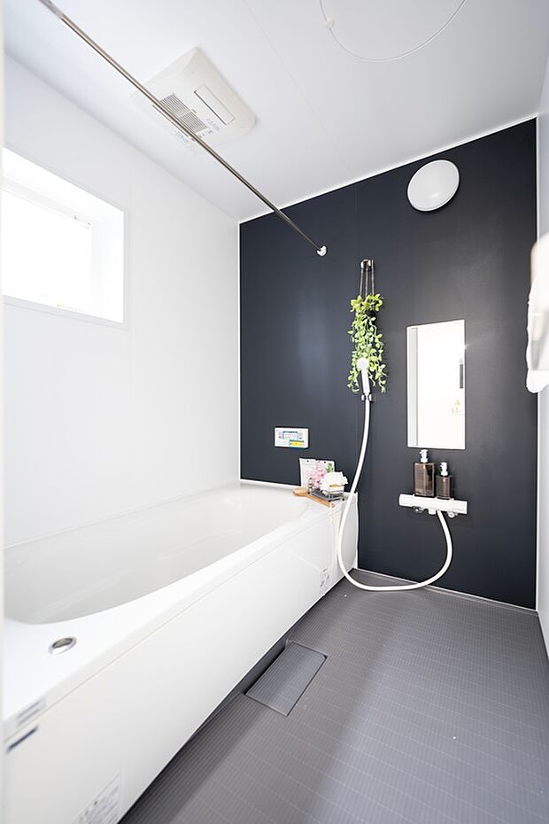 【【1階浴室/B号地】】ブラックのアクセントパネルにより引き締まった印象です。洗い場はカウンターレスで、お掃除がしやすく広々◎バスタブは足を伸ばして寛ぐことができ、高い位置の窓を開けて直接換気を行うことも。