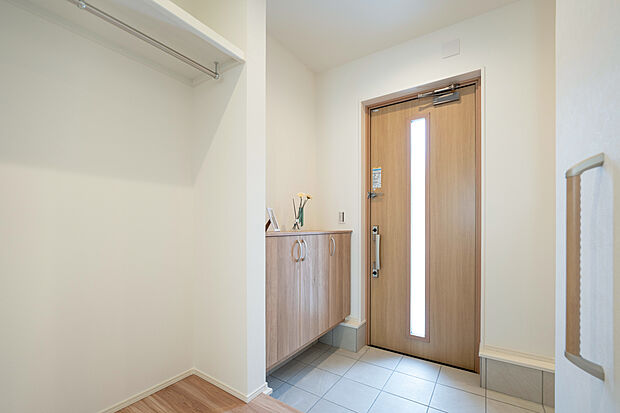 【【1階玄関/B号地】】明るくゆとりあるエントランスが毎日の帰宅をお出迎え。帰宅時は玄関収納と横並びのハンガーパイプにアウターなどを掛けて、身軽になってからリビングや洗面室へ向かうことができます。