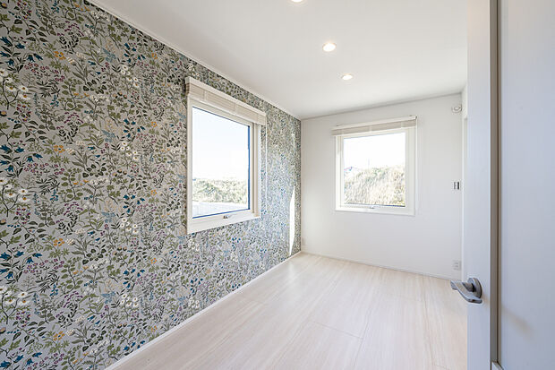 【1階フリールーム】明るく華やかな室内が目を引きます。北欧の歴史ある「ボラスタペーター」のアクセントクロスを使用しました。白い窓枠が外の景色を綺麗に見せます。