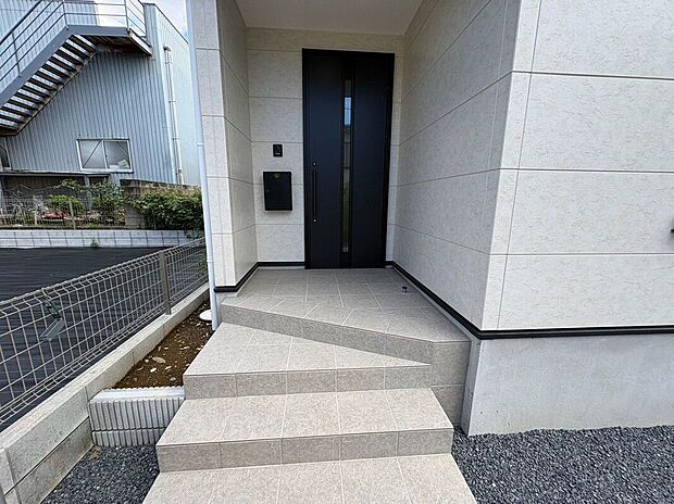 【玄関】屋根のある玄関アプローチで、雨の日も濡れずにスムーズに出入りできます。傘を折りたたむ際や荷物の多い日、お子様のレインコートの脱ぎ着も落ち着いて行える、暮らしの快適さを高める配慮が嬉しい設計です。