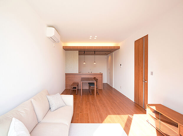 【D棟モデルハウス】18帖のLDKに大きな窓から光が広がり、下がり天井と高い天井が立体的な奥行きをつくる空間。間接照明とダウンライトが陰影を整え、家族が自然と集まる、上質で開放的なリビング