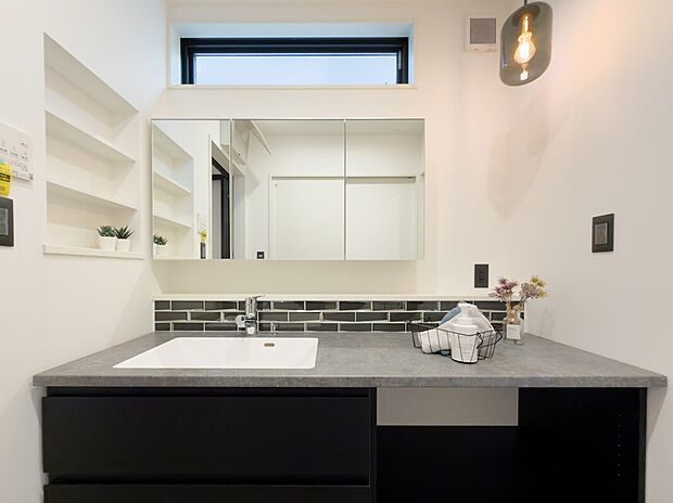 【洗面所】シックなグレーカウンターが落ち着いた印象の洗面化粧台♪ 広々使えて収納力も高く、側面壁に小物置きもあります♪吊り下げ照明と上部窓からの自然光で明るく快適に使え、毎日の身支度や家事がスムーズに進みます♪