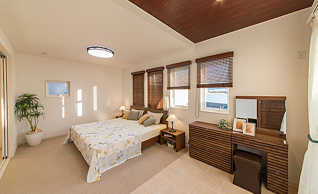 【当社施工例】デザイン性の高い4連の小窓を設けた主寝室です。寝具にドレッサーも置けるゆとりのあるスペースがございます。折り上げ天井がさらに開放感と高級感を演出してくれます。