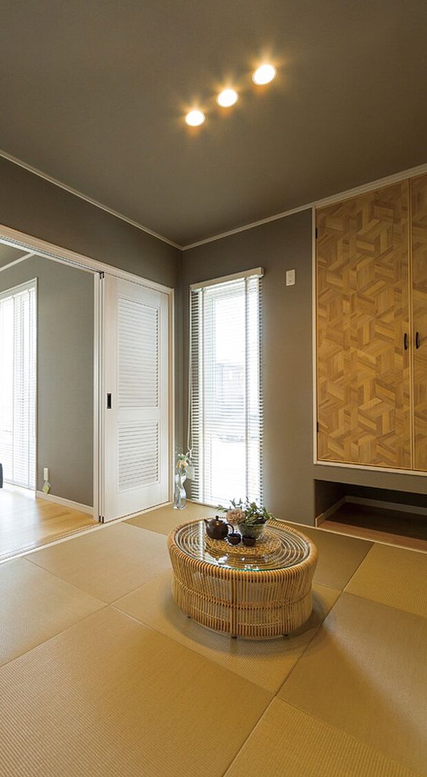 【【当社施工例】】ダークカラーのアクセントクロスを使用すれば一気に落ち着いた印象となります。吊押入の扉のヘリンボーン柄が遊び心を演出しています。リビングと玄関側から出入りでき、生活動線をスムーズに。