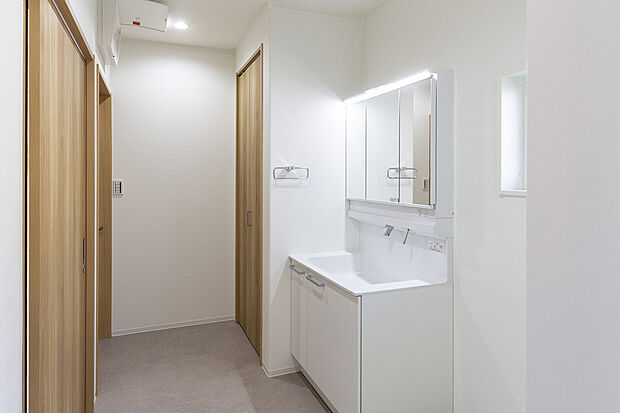 【【1階洗面室/A号地モデルハウス】】洗面室は通常よりも面積が広く、自然換気もできる窓が配置されています。ホワイトで清潔感ある洗面化粧台と横並びのサニタリーは、リネン類や洗剤などの保管に便利です。