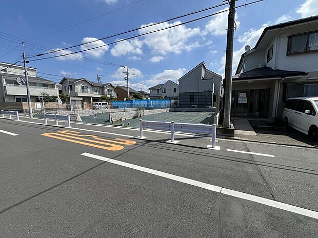【前面道路含む現地写真】青空が広がる住宅街の一角。戸建て住宅が並び、道路沿いには整備された区画が見られます。