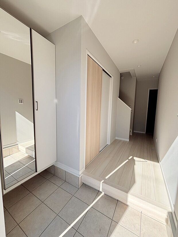 【【施工例】玄関】フロートタイプのシューズクロークは扉に全身鏡付きで身支度もスムーズ。大判タイルで広く見え、掃除も楽な玄関スペースです。