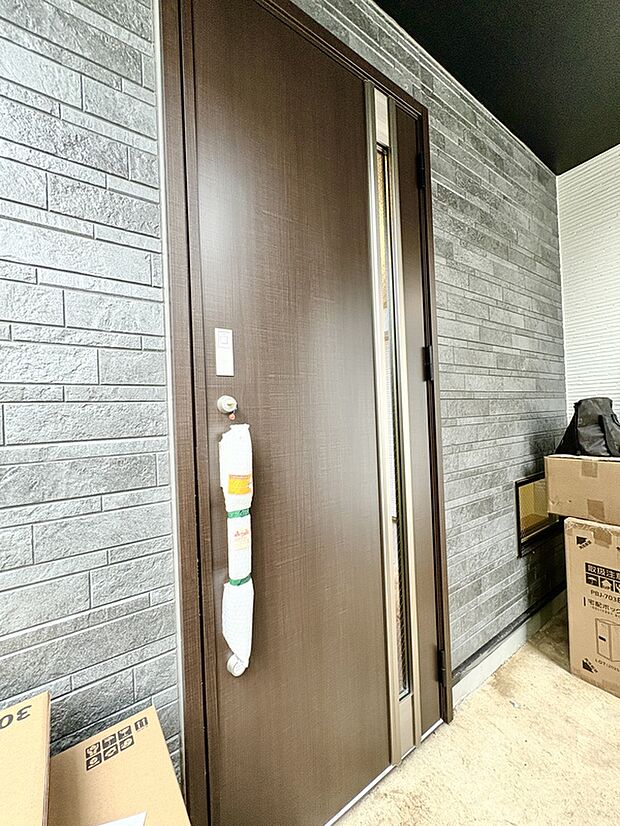 【【玄関(A号棟)】】玄関は屋根があり、雨の日も濡れずに出入りできます。扉のスリットから光を取り込み、玄関が暗くなるのを防いでくれます。