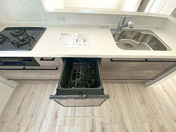 【【キッチン】】広々としたシンクと3口コンロに加え、食洗機などの便利な設備も備えた機能的なシステムキッチンです。リビングへの視界が開けているため、配膳や片付けもスムーズに行えます。時短を叶える工夫が詰まった空間。