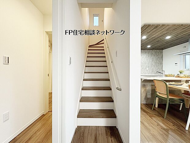 【リビングイン階段】 キッチン横に配置された階段で、上下階の移動もスムーズ。白を基調とした清潔感ある内装に、木目調のアクセントが温かみを添えます。採光窓のある階段は日中も明るく、家族の気配を感じる間取