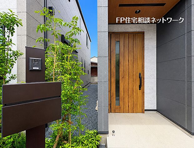 【玄関ポーチ】 重厚感あるデザインが住まいの第一印象を彩る玄関アプローチ。植栽の緑が映える美しい外構とゆとりあるエントランスが、ご家族やゲストを心地よく迎えてくれます。