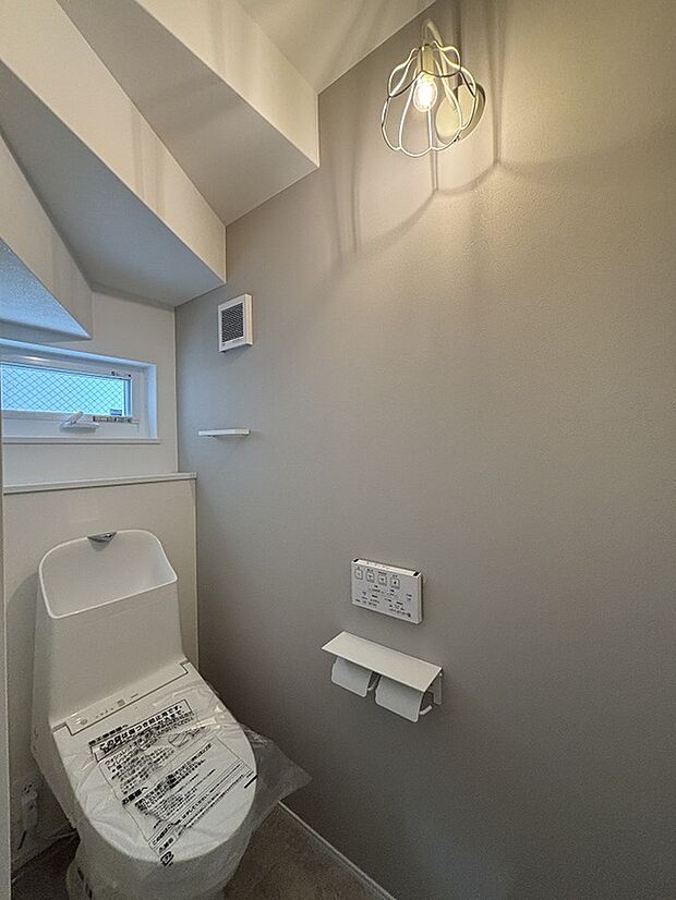 【1階トイレ】階段下のスペースを利用したトイレ。節水タイプで家計に優しいです。お花の形のブラケットライトがかわいい。