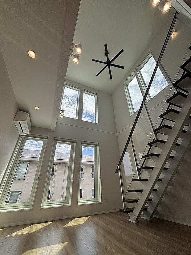 【リビング 吹き抜け】南東向き7面の縦長窓が開放感と明るさをもたらします。