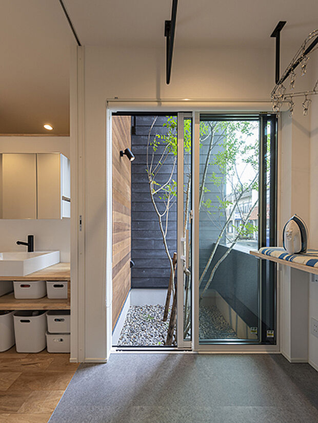 【【プラン例】】坪庭のシマトネリコを眺められる広い脱衣室には、アイロンを掛けたり洗濯物を畳んだりできるカウンターを設置。左にある洗面コーナーは廊下沿いに設けてスぺ―スを節約