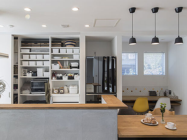 【【プラン例】】モノトーンでまとめたキッチンの腰壁はモルタル仕上げ。背面収納は引き戸で隠すこともできる。ちょっとだけ設けたデスクスペースは、お子様のお勉強スぺース。