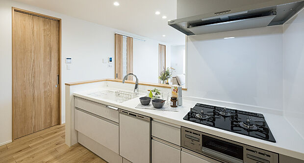 【1階キッチン/1号地モデルハウス】食器洗い乾燥機やタッチレス水栓など、充実機能を搭載。吊戸を設けず開放感を保ちつつ、背面のパントリーにより収納力も確保。シンク横の扉から水回りへすぐで家事効率も◎