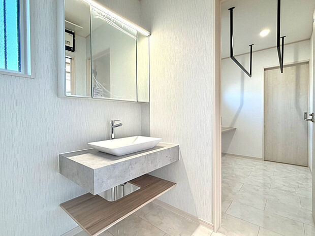 【【洗面室・ランドリールーム】】高級感がありながらスッキリとしたデザインです。隣には物干しが2本ついたランドリールームがあり、干す・アイロンがけ・畳むがこの一室で完結します。収納棚付きで、タオルなどをその場にすぐ片づけられます♪