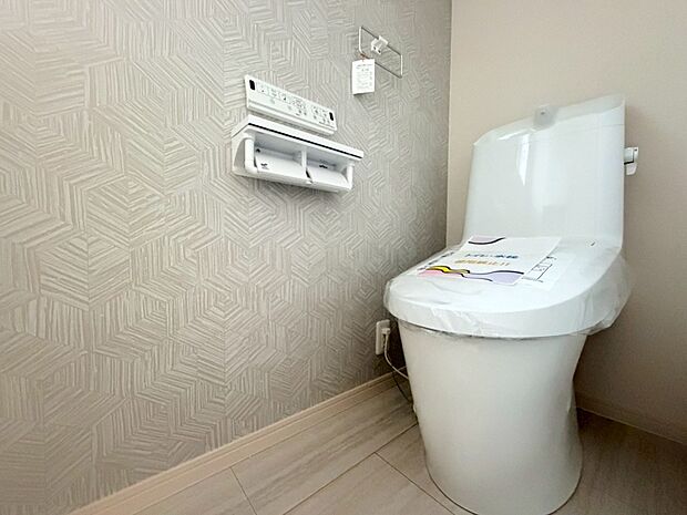 【【トイレ】】フチレス形状やお掃除リフトアップ機能などお手入れのしやすさが特徴。壁設置型のリモコンと２連紙巻き器が備え付けとなっている超節水タイプの温水洗浄便座です。（2026年6月20日撮影）