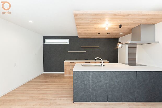 【建物プラン例/LDK】木目の下がり天井とブラックのアクセントが映えるキッチン。落ち着きのあるデザインの中で、料理をしながら家族との会話も自然と生まれる空間です。