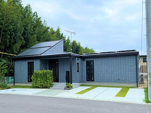 【外観【5号地】(2024年7月撮影)】ロング庇と延長ポーチの重厚感。植栽の緑が映えるブルーグレーの爽やかなカラーリング。広々3台分駐車スペース。