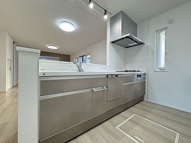 【1号棟 キッチン】落ち着いたグレージュの石目調パネルが美しい、モダンな対面キッチン。リビングを見渡せる開放的な設計で、家族との会話も弾みます。機能性と意匠性を兼ね備えた、洗練された調理空間。