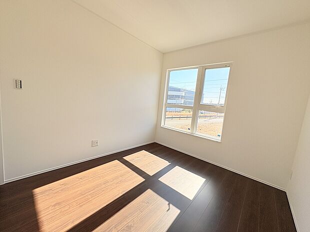 【7号棟 その他居室】日当たり良好な、白を基調とした清潔感あふれる洋室です。落ち着いたダークブラウンのフローリングが、モダンで洗礼された空間を演出。大きな窓からは心地よい光が差し込み、開放感のある暮らしを叶えます。