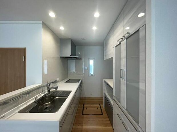 【J棟キッチン】清潔感ある白を基調としたIHクッキングヒーターとビルドイン食洗器付のシステムキッチン。2022年5月撮影）