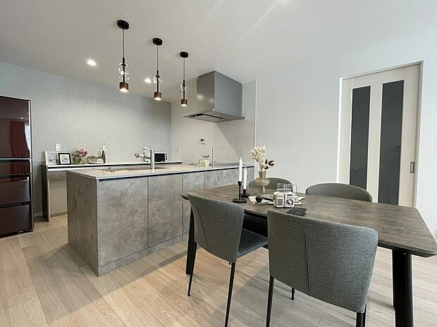 【5号地LDK】
キッチンパネルとダイニングをグレーでまとめた、落ち着きある空間。ペンダントライトがやさしく照らし、素材の質感を引き立てます。大人の雰囲気が漂う心地よいダイニングです。