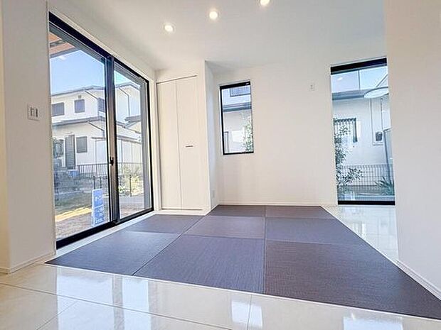 モダンなグレーの畳スペースが心地よい居室。大きな窓から光が差し込み、お子様の遊び場や家族のくつろぎの場として最適です。