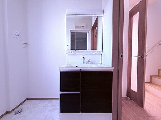 【洗面台・洗面所】大きく見やすい三面鏡で清潔感ある洗面台は、身だしなみチェックや肌のお手入れに最適です。収納も多く、何かと物が増える場所だからこそスッキリと見映えの良い空間に拵えました。時間に余裕とゆとりを持たせます。