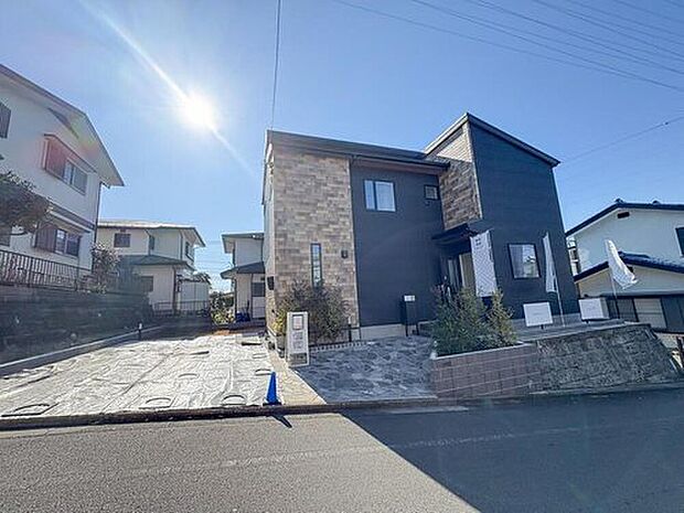 【現地外観写真】陽光が降り注ぐ、洗練されたデザインの住まい。広々とした駐車スペースは、お子様の送り迎えや家族での外出に便利。家族の未来を彩る一邸です。