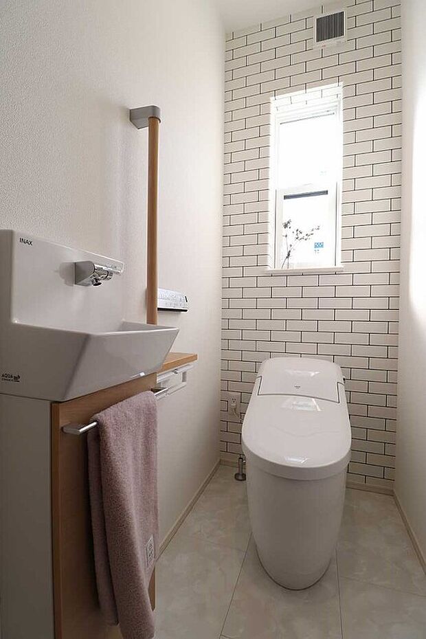 【タイル調のアクセントクロスがお洒落なトイレ】独立した手洗い器や手すりを完備した、ゆとりある設計。小窓からの採光も心地よく、毎日使う場所だからこそデザイン性と利便性にこだわりました。