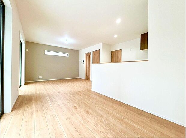 南からの陽光が降り注ぐ、明るく開放的なリビング。木のぬくもりを感じるフローリングとアクセントクロスが、家族の笑顔を育む温かい空間を演出します。