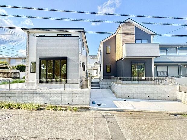 【現地外観写真】青空の下、モダンなデザインが目を引く2棟の住まい。明るい日差しが差し込む空間で、家族の絆を育む毎日を。