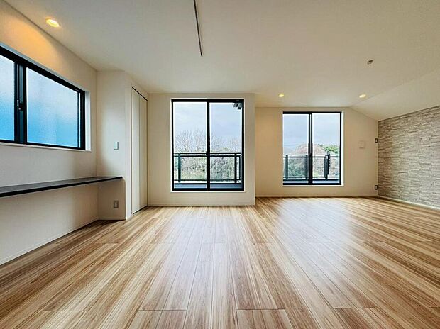 【◇◆リビング◆◇】バルコニー越しに青空と自然の緑が広がる開放的なリビング。フローリングの木目がバルコニー方向に延び、自然と視線を外に導きます。ソファーに腰掛け、ついつい外の景色を眺める、豊かな日常を創り出します。