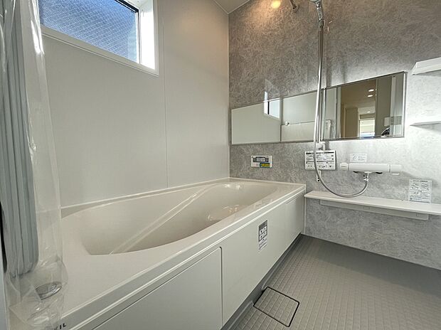 【浴室　A号棟現地写真】■リクシル　システムバスルーム「AX」。フロアはスポンジが奥まで入り掃除がラクラク。また独自の断熱層を使用しているため冬場でも冷やっとしません。