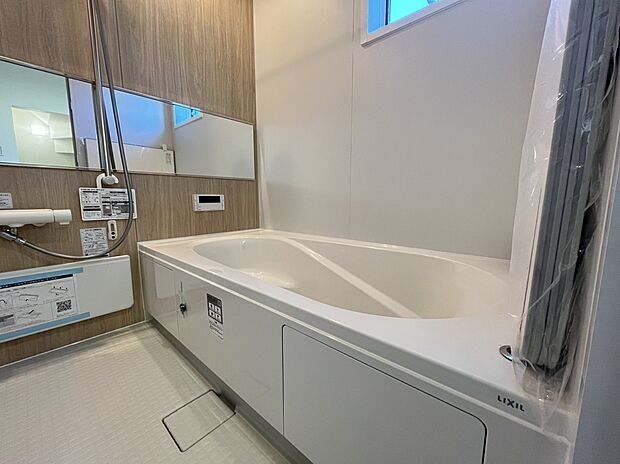 【浴室　B号棟現地写真】■リクシル　システムバスルーム「AX」。フロアはスポンジが奥まで入り掃除がラクラク。また独自の断熱層を使用しているため冬場でも冷やっとしません。