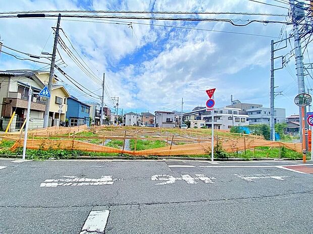 【前面道路含む現地写真】現地(2026年8月)撮影
オレンジの仮囲いで区画分けされた整地済みの分譲地の現地写真。前面はアスファルト舗装の道路(幅員6~9.5m)、周囲に既存住宅があります。