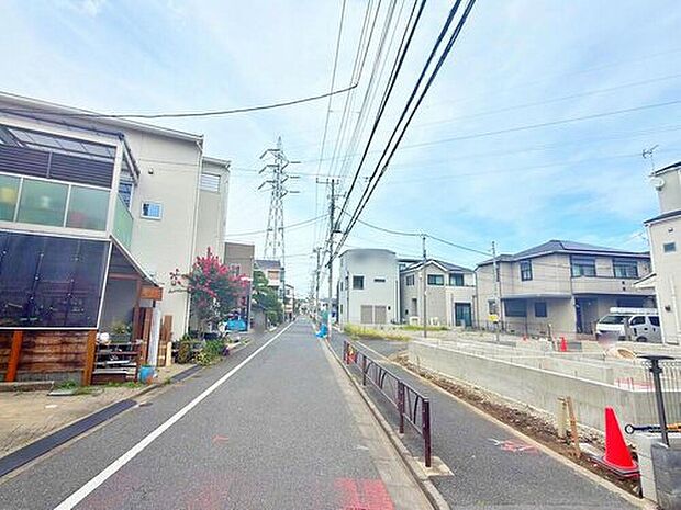 【前面道路含む現地写真】現地(2026年8月)撮影。アスファルト舗装の前面道路(幅員約4.2~7m)と電柱が見える街並み。右手に造成中の区画が確認できます。車種により駐車可。