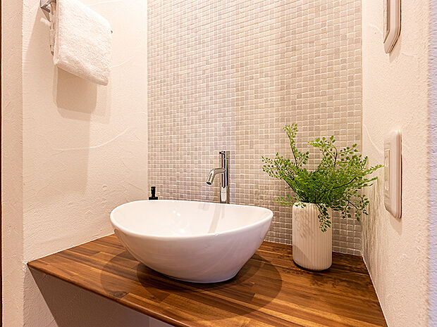 【-】メインの洗面室とは別に、玄関を入ってすぐのところにセカンド洗面台を設置。コロンとしたかわいらしい小型の洗面ボウルは、外から帰ってきてすぐに手洗いとうがいができるので、小さなスペースながら機能的!ウイルスはドアノブから感染につながることもあり、風邪や感染症などの予防になり、いつでも清潔な状態で室内へ。遊んで帰ってきた子供も自然と手洗いが習慣化され、来客時にはわざわざ洗面室を使って頂かなくて済みます。また、壁に施されたモザイクタイルは、遊び心が溢れるデザインでインテリアとしても楽しめると人気です。