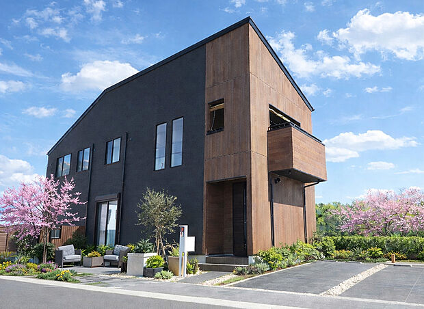 【外観（施工例）】黒と木目が映えるモダン外観、開放的バルコニー付き上質邸宅。
