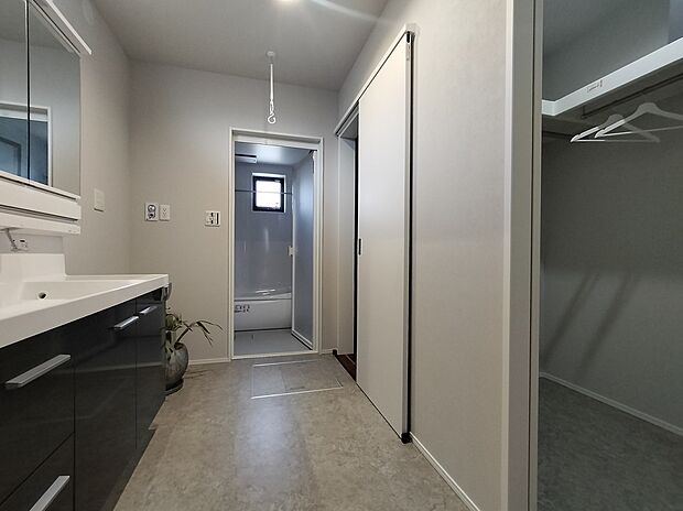 【NO.12 洗面所】収納豊富な洗面台とWICを併設。日用品をスッキリ収めるだけでなく、お風呂上がりの着替えや片付けもその場で完結します。『使う場所にしまう』動線がムダを省き、忙しい毎日の身支度と家事にゆとりを生みます。