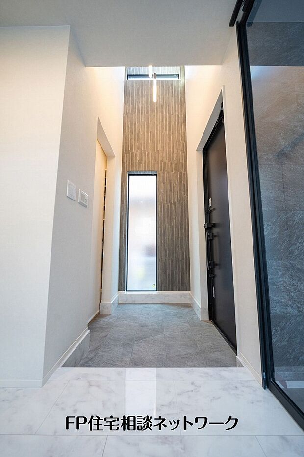 【玄関】縦窓から自然光を取り込むホール空間。シンプルな意匠でまとめ、住まい全体の上質感を引き立てています。