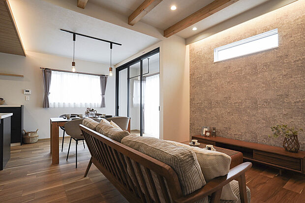 テレビ面の壁には間接照明があり上品な空間。 天井の木梁(むくばり)がアクセントとなり、部屋全体に落ち着いた雰囲気をもたらしています。