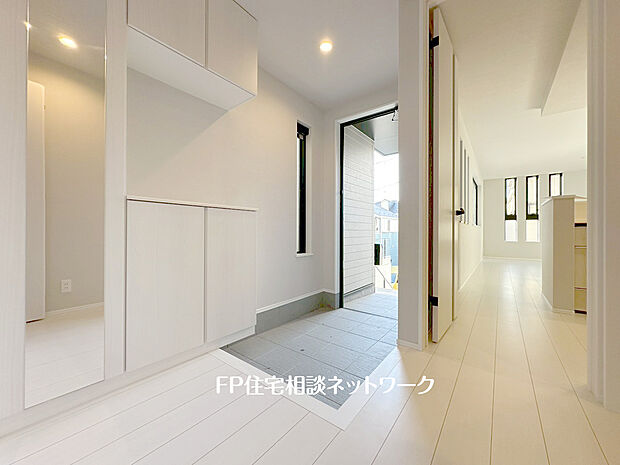 【窓付の明るい玄関　姿見付】（2号棟）大きな窓からは自然光が射し込み訪れる人を心地よく迎え入れる。身だしなみチェックできる姿見付。玄関収納はコの字型で棚があるので、写真や絵を飾ったりなど自分好みのインテリアを楽しめそうです。