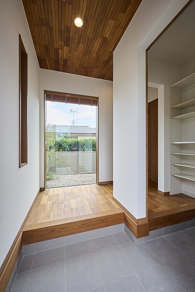 【【レガーレ古賀千鳥2号地】玄関】【2号地】正面に大きな窓を設置し、開放感のある玄関へ。天井には床材の色味と合わせたチークの天然木を貼り、高級感を演出いたしております。また玄関・ホールから出入りのできる広々シューズクロークも配置